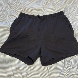 Svarta shorts från H&M  - Säljer ett par svarta shorts från H&M  i storlek L. De är i mycket bra skick och har en elastisk midja med dragsko för justerbar passform. Perfekta för en avslappnad dag eller träning. Materialet är mjukt och bekvämt.