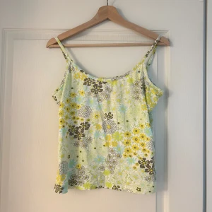 Blommigt linne  - Säljer ett sött linne med blommigt mönster i ljusa pastellfärger från gianini. Justerbara axelband. 