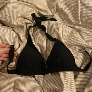 Svart bikiniöverdel - Säljer en stilren svart bikiniöverdel i trekantsmodell. Den har knytband i nacken och ryggen för justerbar passform. Perfekt för sommarens stranddagar eller poolhäng. Materialet känns mjukt och bekvämt mot huden. Passar bra till både bad och solning. 🖤använd i pool / luktar lite klor