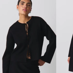 Svart kofta med knytning - Snygg svart kofta med knytning framtill. Perfekt för både vardag och fest. Den har långa ärmar och en stilren design som passar till det mesta. Ett måste i garderoben för en chic look!