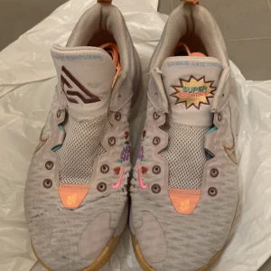 Nike Giannis Antetokounmpo sneakers - Säljer ett par unika Nike Giannis Antetokounmpo sneakers i bra skick 5/10. Skorna är färgglada och har en cool design med broderade mönster. De är perfekta för både träning och vardag. Storlek herr 44. Snören skickas med!