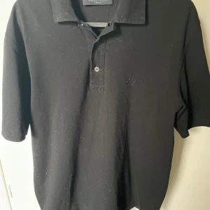 Svart pikétröja från Valentino - Snygg svart pikétröja från Valentino i storlek L men passar M. Perfekt för en stilren och avslappnad look. Tröjan har en klassisk krage och knappar framtill. Passar både till vardags och festligare tillfällen.