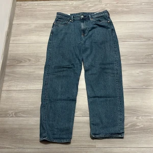Blå loose fit jeans från H&M - Säljer ett par blå loose fit jeans från H&M. De har en klassisk femficksdesign med knapp och dragkedja i gylfen. Perfekta för en avslappnad stil och passar till de flesta tillfällen. Skriv vid frågor och funderingar😊