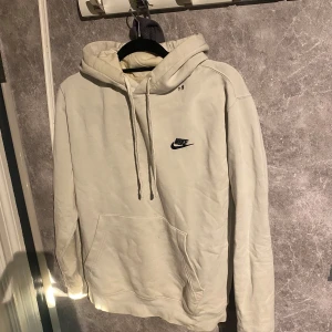 Krämfärgad hoodie från Nike - Säljer en hoodie från Nike i storlek M. Det finns några små hål vid halsen, men annars i bra skick. 