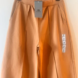 Beige byxor från LIB - Säljer ett par snygga beige byxor från LTB .De har en loose passform och är perfekta för både vardag och fest. Byxorna är högmidjade och har en stilren design utan mönster. Materialet känns mjukt och bekvämt, vilket gör dem perfekta för höst och vår.