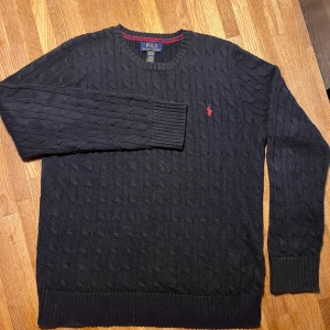 Mörkblå stickad tröja från Polo Ralph Lauren - Mörkblå kabelstickad tröja från Polo Ralph Lauren. Passar både till vardags och lite finare tillfällen! XL 18-20 år, fint skick!