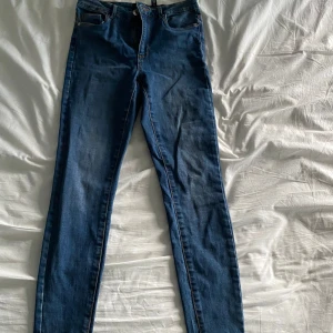 Blå jeans från Vero Moda - Säljer ett par fina blå skinny jeans från Vero Moda i storlek S. De har en snygg och enkel design med fem fickor och är högmidjade. Perfekta för vardagsbruk och kan matchas med det mesta i garderoben.