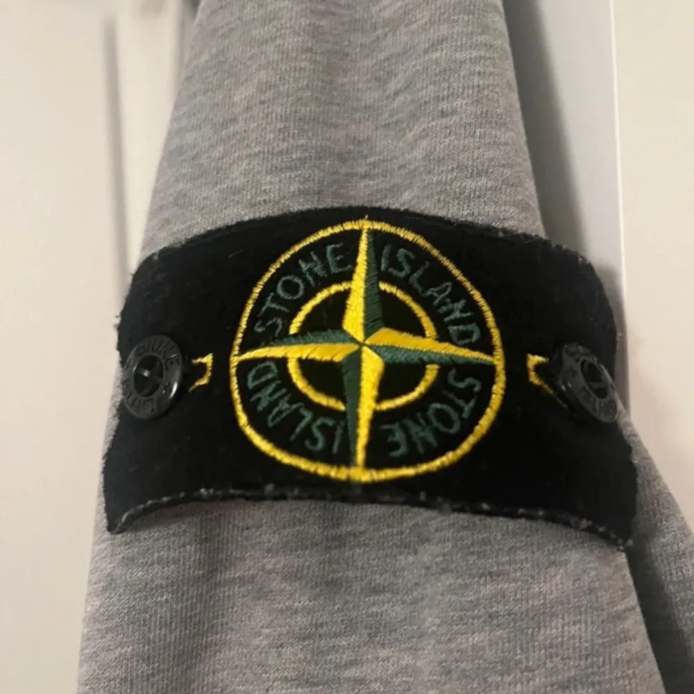 Säljer en snygg grå sweatshirt från Stone Island i mycket bra skick. Den har en klassisk rund hals och långa ärmar med det ikoniska Stone Island-märket på ärmen. Perfekt för både vardag och chill dagar. Passar till allt och är superbekväm!. Tröjor & Koftor.