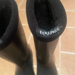 Svarta stövlar från Equipage - Säljer ett par svarta stövlar från Equipage i mycket bra skick. De är perfekta för höst och vinter med sin robusta design och slitstarka sula. Stövlarna är gjorda av syntetmaterial och har en stilren look som passar till det mesta. Perfekta för regniga dagar eller en promenad i skogen. Klarar kylan mot -40grader. 