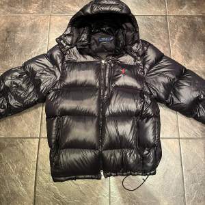 Säljer en snygg svart pufferjacka från Polo Ralph Lauren i storlek XL. Jackan är riktigt varm, perfekt för kalla dagar. Den är mycket sparsamt använd och ser i princip ny ut. Inga märken eller liknande. Perfekt för vintern! Fler bilder kan ordnas och några hundralappar billigare vid snabb affär.