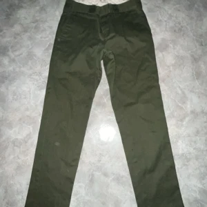 Dickies byxor gröna - Säljer ett par gröna slim fit byxor i bra skick. Perfekta för både vardag och lite mer uppklädda tillfällen. De har en klassisk design med knappar och dragkedja framtill. Passar bra till höst- och vårsäsongen.