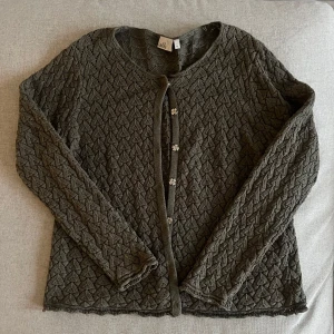 Grön stickad kofta från Isolde - Grön virkad kofta med knäppe. Super enkel att knäppa och knäppa upp! Bekväm o knäppt tecken på användning. Det står storlek L men sitter bra i passform på mig som har S/M.
