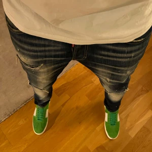 DSQUARED2 JINZZ - Säljer ett par mörkblå DSQUARED2 jeans med slitningar och en cool, distressed look. Perfekta för en brutal outfit. De har en normal passform och väldigt bekväma! Väldigt populära dessutom!❤️⭐️Slim Jinzz kan gå ner rejält i pris vid snabb äffär!