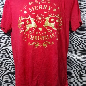 Röd jultröja med guldtryck - Säljer en röd t-shirt med ett glittrigt guldtryck som säger 'Merry Christmas' och har renmotiv. Perfekt för julfirandet! Tröjan är kortärmad och i bra skick. 🎄✨