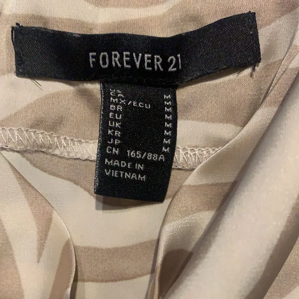 Säljer en superfin beige och vit zebramönstrad klänning från Forever 21. Den är axelbandslös och har en avslappnad passform, perfekt för sommardagar eller en utekväll. Materialet känns lätt och luftigt. Passa på att köpa denna trendiga klänning!. Klänningar.