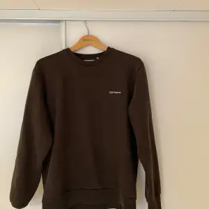 Säljer en snygg brun sweatshirt från Carhartt i storlek L men den är mer som en M för att den är kort. Tröjan är i bra skick och perfekt för både höst och vinter. Den har en klassisk design med rund hals och långa ärmar. Perfekt för en avslappnad stil eller lager på lager-look. 🧥