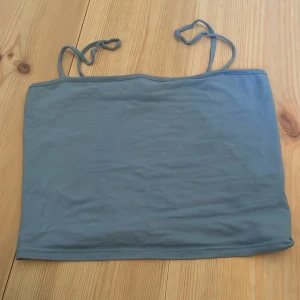 Blå tubtopp från H&M Divided - Säljer en enkel och stilren blå tubtopp från H&M Divided i storlek S. Perfekt för sommardagar eller som ett basplagg under andra toppar. Den är i bra skick och har smala axelband som har och går att knyta!