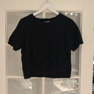 Svart fluffig tröja med korta ärmar  - Mysig svart tröja med korta ärmar och fluffigt material. Köpt från Vila för 400kr, använd fåtal gånger så i bra skick, storlek L men sitter som M, säljer för 250kr 