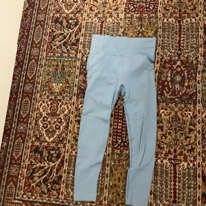 Ljusblå leggings - Säljer ett par ljusblå leggings i mycket bra skick. De är tillverkade av 92% polyamid och 8% elastan, vilket gör dem superstretchiga och bekväma. Perfekta för träning eller en avslappnad dag hemma. Högmidjade för extra komfort och stil. Passar perfekt till både vardag och träning!