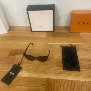Bruna solglasögon från Fendi - Snygga bruna solglasögon från Fendi i mycket bra skick. De har en klassisk rund form och kommer med ett elegant fodral. Perfekta för att ge en touch av lyx till din outfit. Passar både för vardag och fest!