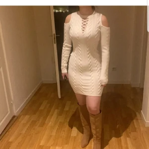 Vit stickad klänning från Guess - Säljer en superfin vit stickad klänning från Guess i HELT NY. Den har en tight passform med snygga cut-out detaljer på axlarna och ett snörat mönster framtill. Perfekt för höst och vinter med ett par boots. 👢 Formar kroppen så fint 😀använd köp nu❤️