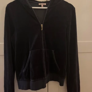 Svart hoodie från Juicy Couture - Säljer en svart Juicy Couture hoodie i storlek XL dock väldigt liten i storleken. Den har en dragkedja framtill och en snygg broderad design med blommor och logga på baksidan. ❤️