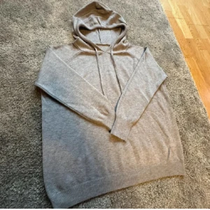 Grå hoodie i 100% merinoull - Säljer en supermjuk och bekväm grå hoodie i merinoull . Perfekt för kyliga dagar med sin långa ärmar och klassiska huva. Den har en enkel design med ribbade muddar och dragsko vid huvan. Passar perfekt för både vardag och mysiga hemmakvällar. Passar dig mellan 160-170!. 🩶