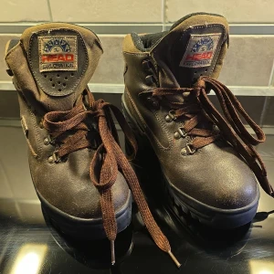 Bruna kängor från Head - Säljer ett par robusta bruna kängor från Head i storlek herr 41. De är gjorda av skinn och syntetiska material med en slitstark gummisula. Perfekta för höst- och vinteräventyr med snörning för bra passform. Använda men i bra skick!