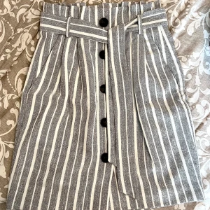 Högmidjad kjol  - Randig högmidjad kjol med knytdetalj i midjan. Kjolen är storlek 34 från HM.  