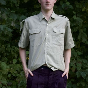 Beige kortärmad skjorta - Säljer en stilren beige kortärmad skjorta med två bröstfickor och knappar framtill. Perfekt för sommardagar eller avslappnade tillfällen. Skjortan har en klassisk krage och är i ett lätt material som känns skönt mot huden.