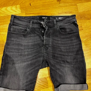 Svarta jeansshorts från Replay - Snygga svarta jeansshorts från Replay med klassisk femficksdesign och uppvikta ben. Perfekta för en avslappnad stil. Midjemått 32 tum.