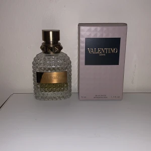 Valentino Uomo Eau de Toilette 20 ml - Säljer en elegant Valentino Uomo Eau de Toilette i en lyxig flaska med nitar och ett mönstrat glas. Doften är maskulin och sofistikerad, perfekt för den stilmedvetne. Den passar även perfekt nu i vinter!Och till dig som gillar att byta dofter hela tiden (för att det inte finns så mycket kvar).Flaskan rymmer 50 ml och kommer i en stilren förpackning.                                                                    Den har använts, finns lite mindre än halva kvar. Så ungefär 20-25ml