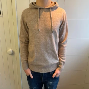 Merinoull Hoodie - En otroligt snytt Merinoull Hoodie i en beige färg! Storlek S. Modellen är 179 cm lång. Använd max 3 gånger, inga defekter! Hör av dig vid intresse eller minsta fundering!😊
