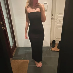 Svart axelbandslös klänning - Snygg svart axelbandslös klänning med en elegant slits baktill. Perfekt för en stilren look. Klänningen är lång och har en tight passform som framhäver figuren. Xs men passar också S❤️