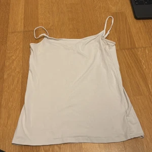 Vit ärmlös linnetopp - Säljer en enkel och stilren vit linnetopp med smala axelband. Perfekt för varma sommardagar eller som ett basplagg i garderoben.