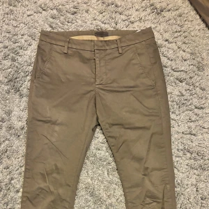 Bruna/mörkgröna chinos från Dondup - Snygga gröna/bruno chinos från Dondup i storlek w29. De har en klassisk design med knappar bak och bälteshällor. Perfekta för en stilren look. köpta för 2999 på NK. Använda 2 gånger 