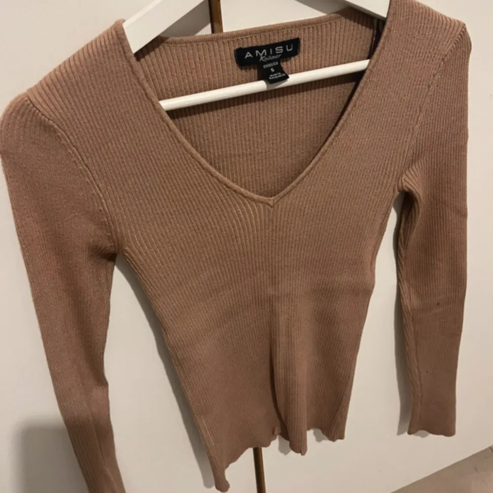Säljer en beige ribbad tröja från Amisu. Tröjan har en v-ringad design och långa ärmar, perfekt för en bekväm look. Passar utmärkt till både jeans och kjol. . Neuletakit & Villapaidat.