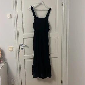 Svart långklänning från H&M - Snygg svart långklänning från H&M med breda axelband och knytning i midjan. 