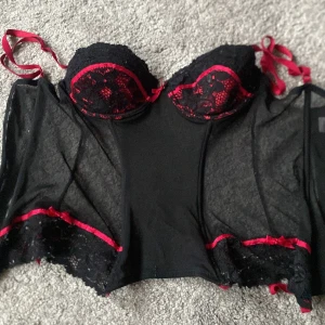 Röd korsett med rosa rosetter  - Säljer min Röda Ava rosé korsett som inte kommer till användning längre men är i bra skick. Den har små röda rosetter som sitter på sidan och en i mitten vid Bhn 🎀