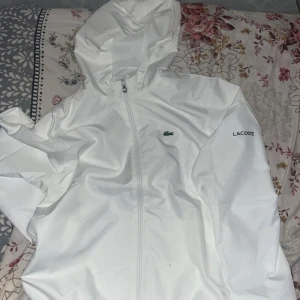 Lacoste windbreaker - Säljer denna vita lacoste windbreaker för att beställde i fel storlek. Köpt för 2 dagar sen och fortfarande i paketet.