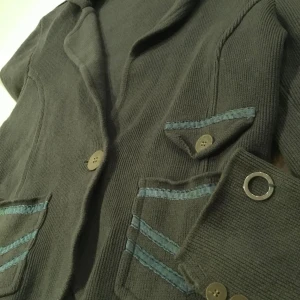 Grön kavaj från Stockh LM - Snygg militärgrön kavaj från Stockh LM med unika detaljer.Fickorna är dekorerade med ett subtilt mönster i mörkare nyanser. Perfekt för en stilren look. Passar S/M