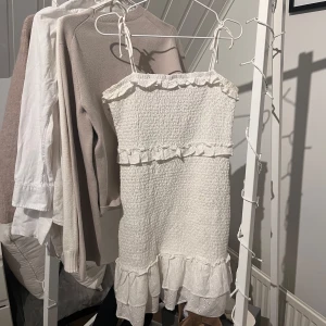 Vit klänning - Fin vit klänning med smockdetaljer och volangkant. Perfekt till student eller konfirmation💕