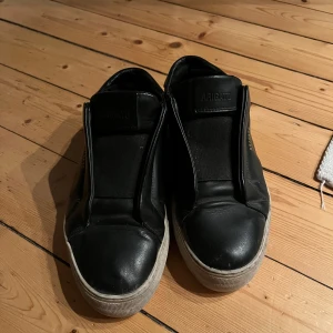 Svarta sneakers från Axel Arigato - Snygga svarta sneakers från Axel Arigato som har lite skavanker därav priset