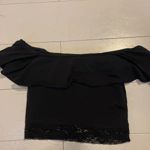 Svart offshoulder topp med spetsdetalj  - Snygg svart offshoulder topp med volang och spetsdetalj vid nederkanten. Perfekt till sommaren☀️Passar bra till både jeans och kjol. Säljer pga att den har blivit för liten 