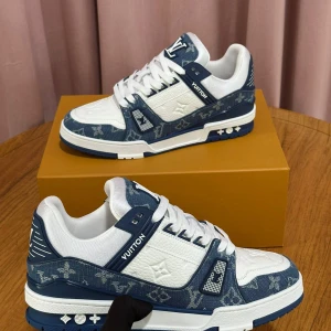 Blå och vita sneakers från Louis Vuitton - Snygga sneakers från Louis Vuitton i blått och vitt med det ikoniska monogrammönstret. Skorna har snörning och en bekväm sula, perfekt för en stilren look.