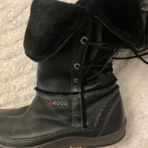 Svarta vinterstövlar från Ecco - Säljer ett par svarta vinterstövlar från Ecco i skinn med snörning och mjukt foder. Perfekta för kalla dagar med sin robusta design och bekväma passform.