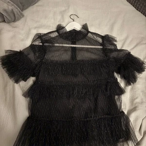 Svart glittrig topp - Säljer en superfin svart festtopp från By Malina med glittrigt mönster. Använd endast en gång och i superskick!❤️