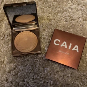 CAIA Bronzer - Säljer en snygg bronzer från CAIA i en elegant roséguldfärgad förpackning. Perfekt för att ge ansiktet en solkysst look med en naturlig glöd. Kompakt design med spegel, vilket gör den enkel att ta med sig. Använd för att framhäva kindben och ge ansiktet en varm ton. Lite använd men kommer tyvärr inte till användning 