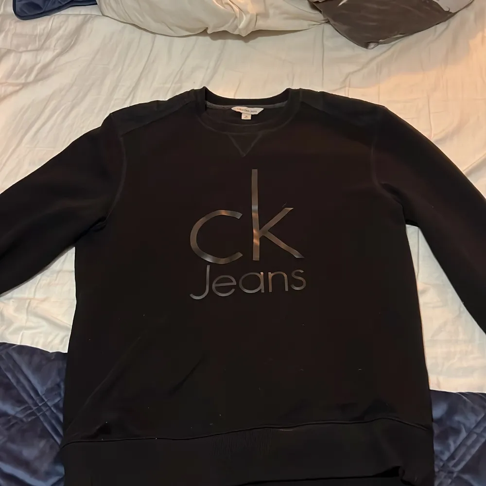 Säljer en stilren svart tröja från Calvin Klein Jeans i storlek M men ganska stor i storleken! Tröjan har en klassisk design med långärmade ärmar och en diskret logga på framsidan. Perfekt för både vardag och festliga tillfällen. Skön och enkel att matcha med det mesta i garderoben. Tröjan kommer i mycket bra skick 10/10!. Tröjor & Koftor.