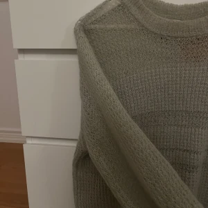 Grön stickad tröja från Weekday - Säljer en superfin grön stickad tröja från Weekday i storlek S. Perfekt för kyliga dagar med sin mysiga och luftiga design. Tröjan har en normal passform och långa ärmar, vilket gör den idealisk för både höst och vinter. Tröjan är lite mer genomskinlig på vissa ställen vilket skapar en cool och unik effekt. 🍂